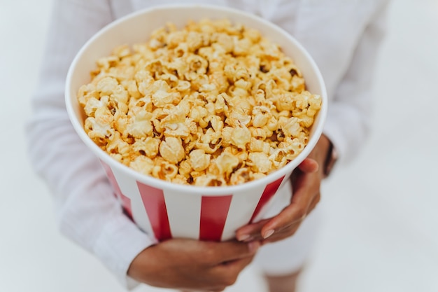 Kostenloses Foto nahaufnahmefoto eines jungen süßen mädchens, das eine tube popcorn in ihren händen hält.