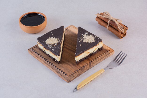 Nahaufnahmefoto von frischen Schokoladenkuchenscheiben mit Zimt und Gabel über Grau