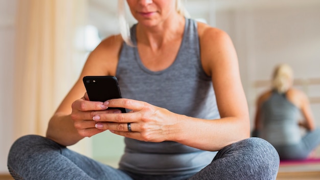 Nahaufnahmefrau an der Sportkleidung Telefon überprüfend