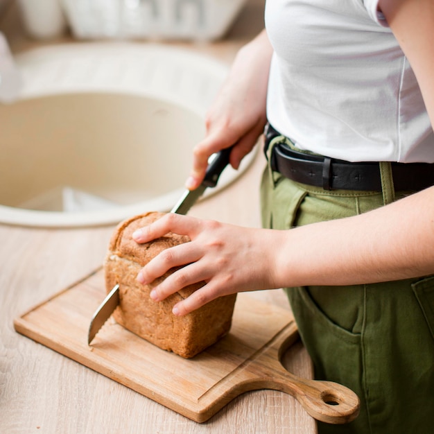 Nahaufnahmefrau, die Bio-Brot schneidet