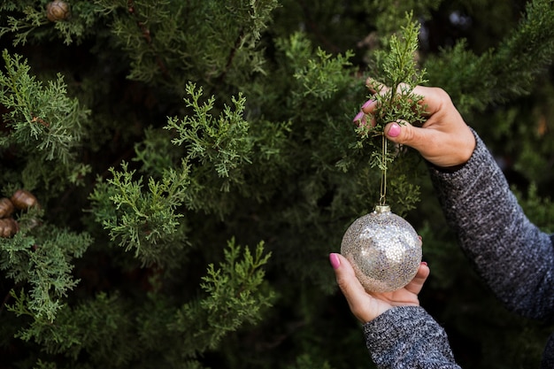 Nahaufnahmefrau, die den Weihnachtsbaum mit Kugel verziert