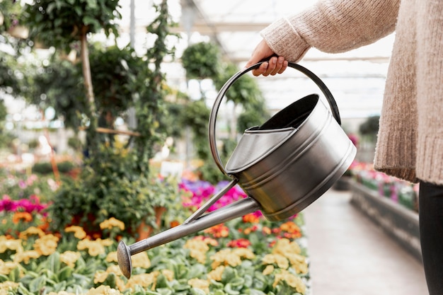 Nahaufnahmefrau, die die Blumen wässert