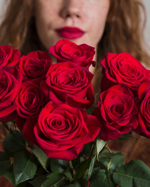 Nahaufnahmefrau, die einen Blumenstrauß von Rosen hält