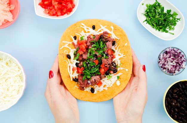 Nahaufnahmefrau, die entfalteten Burrito mit blauem Hintergrund hält