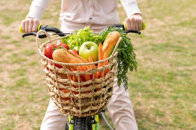 Nahaufnahmefrau, die Fahrrad mit Lebensmitteln reitet