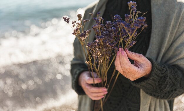 Nahaufnahmefrau, die lila Blumen im Freien hält