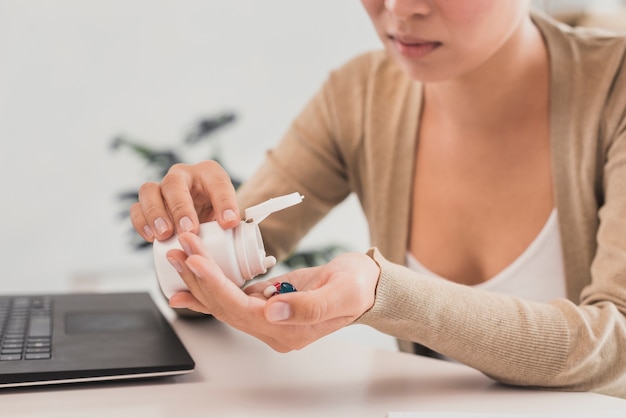 Nahaufnahmefrau, die Pillen im Büro einnimmt