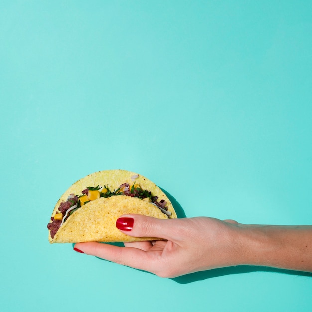 Nahaufnahmefrau, die Taco mit grünem Hintergrund und Kopieraum hält