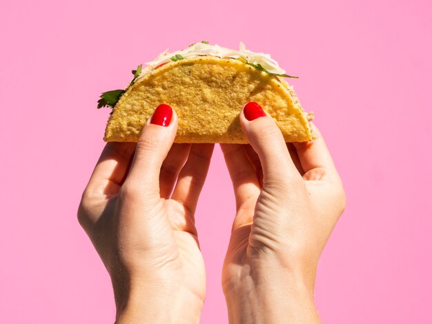 Nahaufnahmefrau, die Taco mit rosa Hintergrund hält