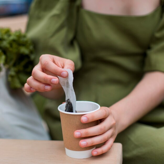 Nahaufnahmefrau, die Teebeutel aus Tasse nimmt