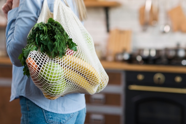 Nahaufnahmefrau, die wiederverwendbare Tasche mit Bio-Lebensmitteln trägt