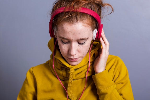 Nahaufnahmefrau mit gelbem Hoodie und Kopfhörern