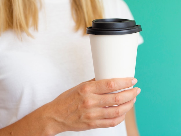 Nahaufnahmefrau mit Kaffeetasse und grünem Hintergrund