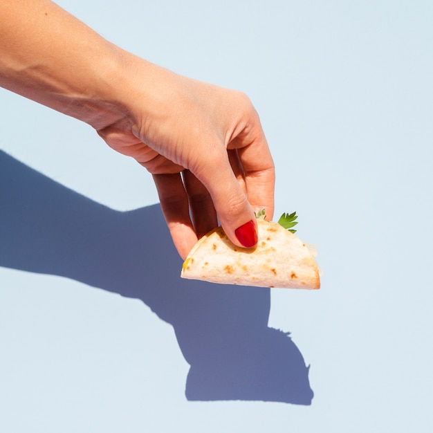 Nahaufnahmefrau mit kleinem Taco und blauem Hintergrund