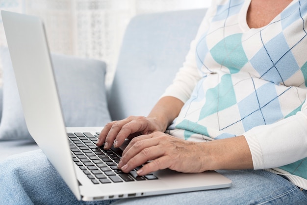 Nahaufnahmefrau mit Laptop auf der Couch