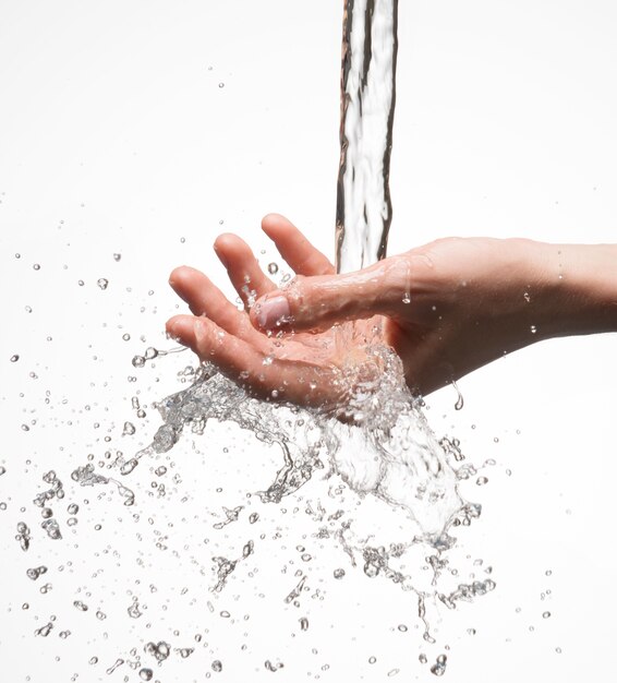 Nahaufnahmefrauenhand unter dem Strom des Spritzwassers - Hautpflegekonzepts