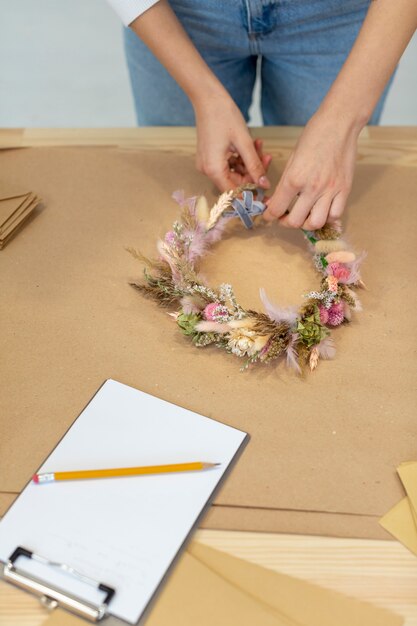 Nahaufnahmegeschäftsperson, die einen Kranz der Blumen hohe Ansicht schafft