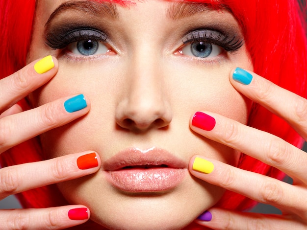 Kostenloses Foto nahaufnahmegesicht eines schönen mädchens mit hellen mehrfarbigen nägeln.