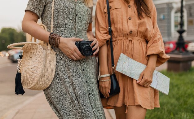 Nahaufnahmehände Details Zubehörtasche, Karte, Fotokamera von stilvollen jungen Frauen, die im Frühjahr zusammen reisen, trendig gekleidet, Streetstyle