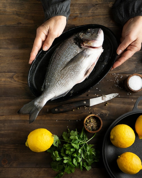 Kostenloses Foto nahaufnahmehände, die tablett mit fisch halten