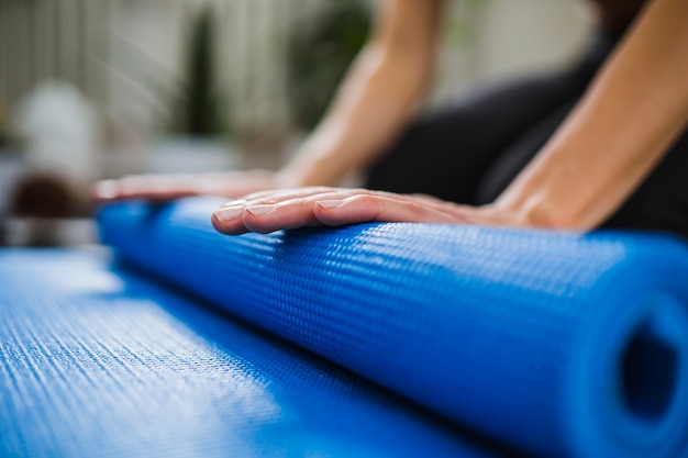 Kostenloses Foto nahaufnahmehände, die yogamatte aufrollen