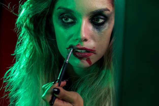 Nahaufnahmehalloween-Mädchen, das einen Pinsel für ihre Lippen verwendet