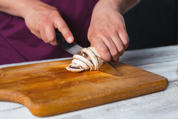 Nahaufnahmehand des Kochbäckers, der Pizza an der Küche macht