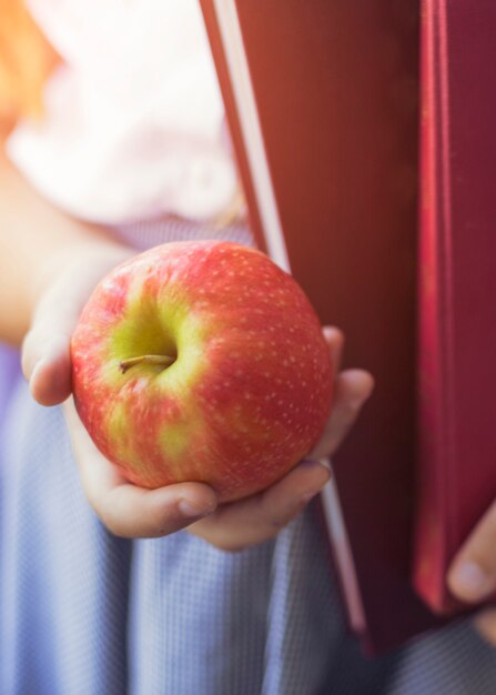 Nahaufnahmehand des Schulmädchens mit Apfel