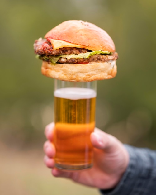 Kostenloses Foto nahaufnahmehand, die burger oben auf glas hält