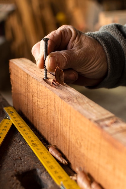 Kostenloses Foto nahaufnahmehand, die einen nagel im holz hält