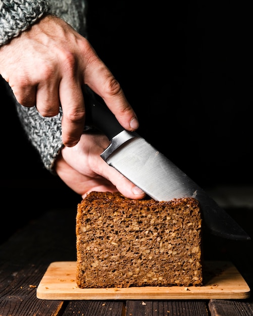 Nahaufnahmehand, die selbst gemachtes Brot schneidet