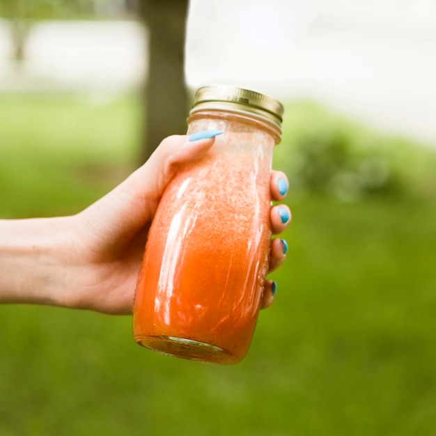 Nahaufnahmehand, die Smoothieflasche hält