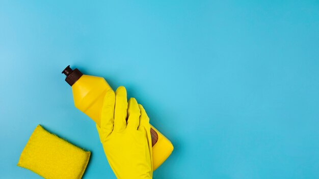 Nahaufnahmehand mit gelbem Handschuh auf blauem Hintergrund