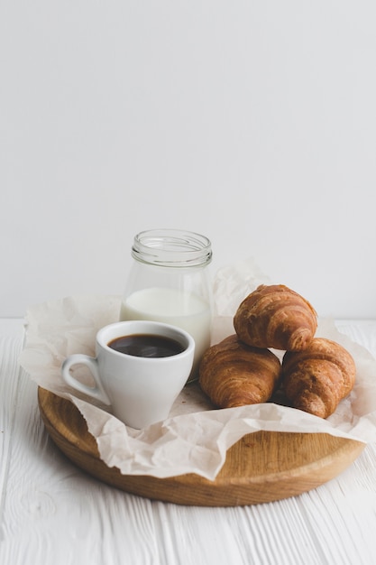 Nahaufnahmekaffee und Hörnchen auf Behälter