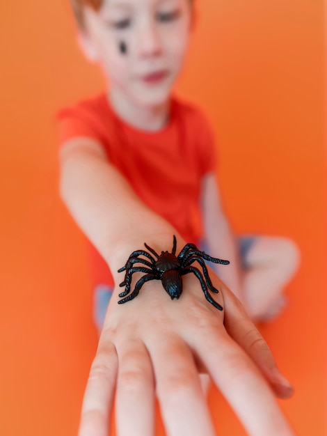 Nahaufnahmekind, das Halloween-Spinne an Hand hält