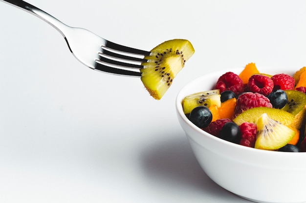 Kostenloses Foto nahaufnahmekiwi auf gabel mit schüssel frucht