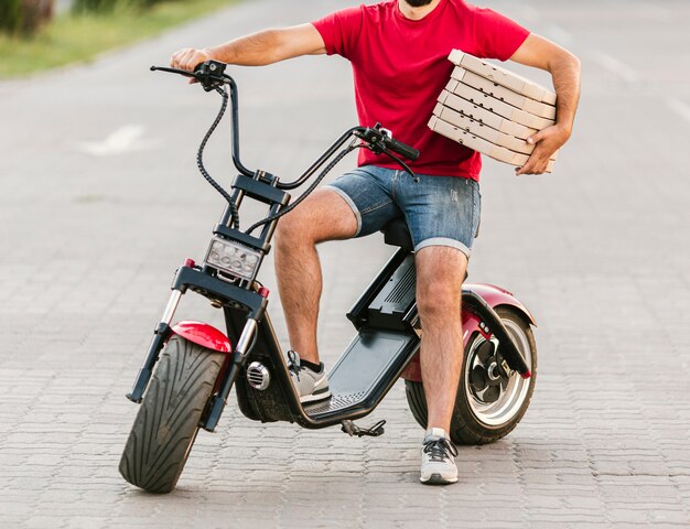 Nahaufnahmelieferant auf Motorrad mit Pizza