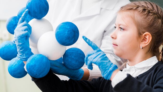 Nahaufnahmemädchen mit Handschuhen, die Chemie lernen