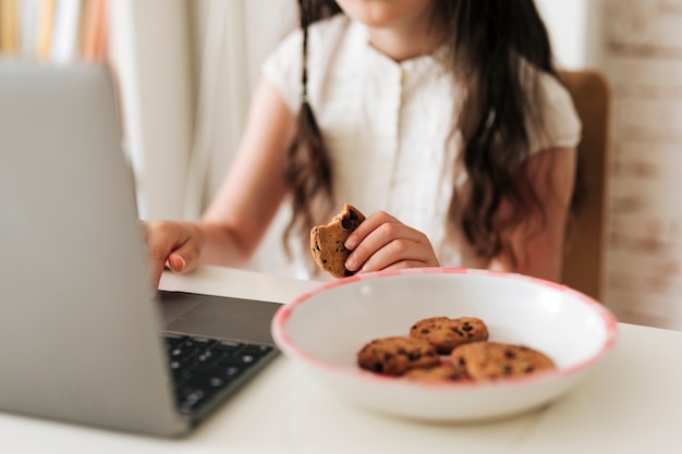 Nahaufnahmemädchen mit Laptop und Plätzchen