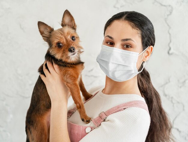 Nahaufnahmemädchen mit Maske, die Hund hält