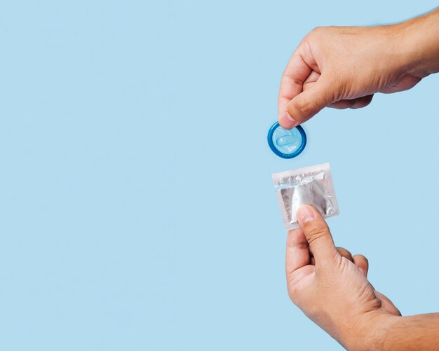 Nahaufnahmemann, der blaues Kondom auspackt