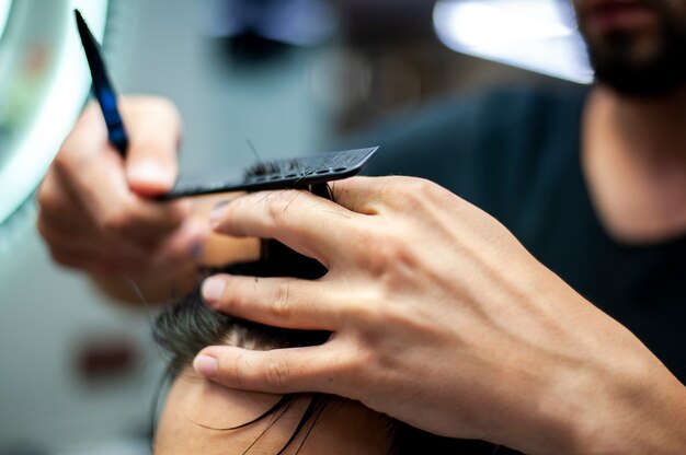 Nahaufnahmemann, der Kundenhaar kämmt