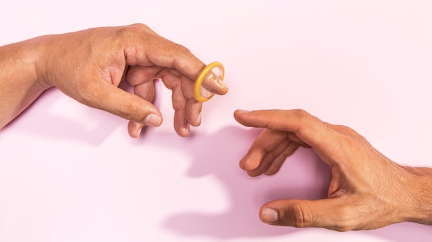 Nahaufnahmemannhände mit transparentem Kondom