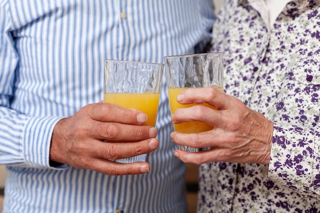 Nahaufnahmepaare, die Gläser mit Saft halten