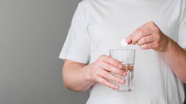 Nahaufnahmepatient, der Pille in Wasser setzt