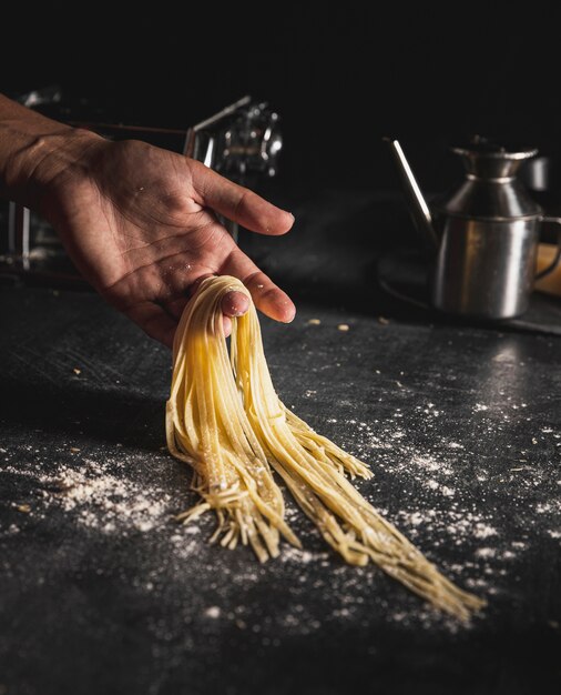 Nahaufnahmeperson, die Spaghettis mit einer Hand hält