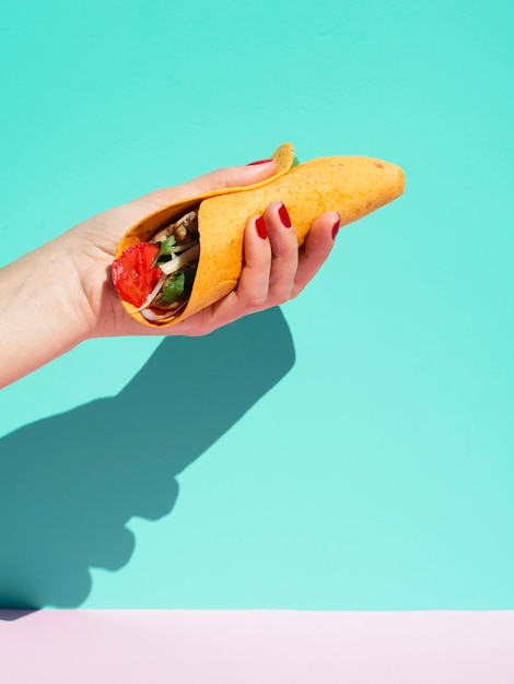 Nahaufnahmeperson mit Burrito und blauem Hintergrund