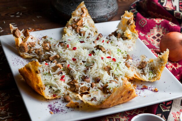 Nahaufnahmepilaf in einer Pita mit Fleisch, Bohnen und Gewürzen. traditionelles orientalisches Gericht auf einem dunklen Holztisch horizontal