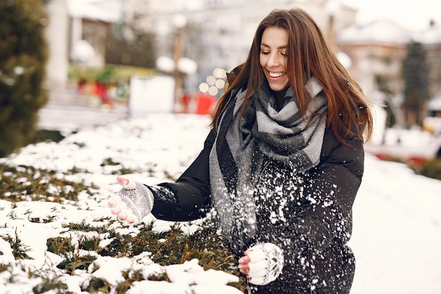 Nahaufnahmeporträt der Frau in der schwarzen Jacke, die mit dem Schnee spielt