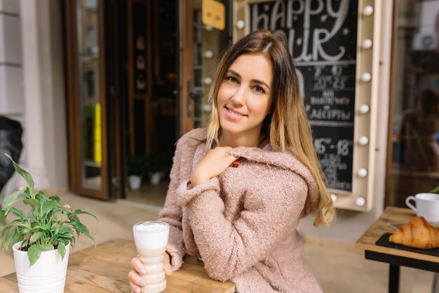 Nahaufnahmeporträt der Frau sitzt auf der Straße und trinkt Kaffee